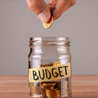 Placing a coin in a jar labelled 'BUDGET'